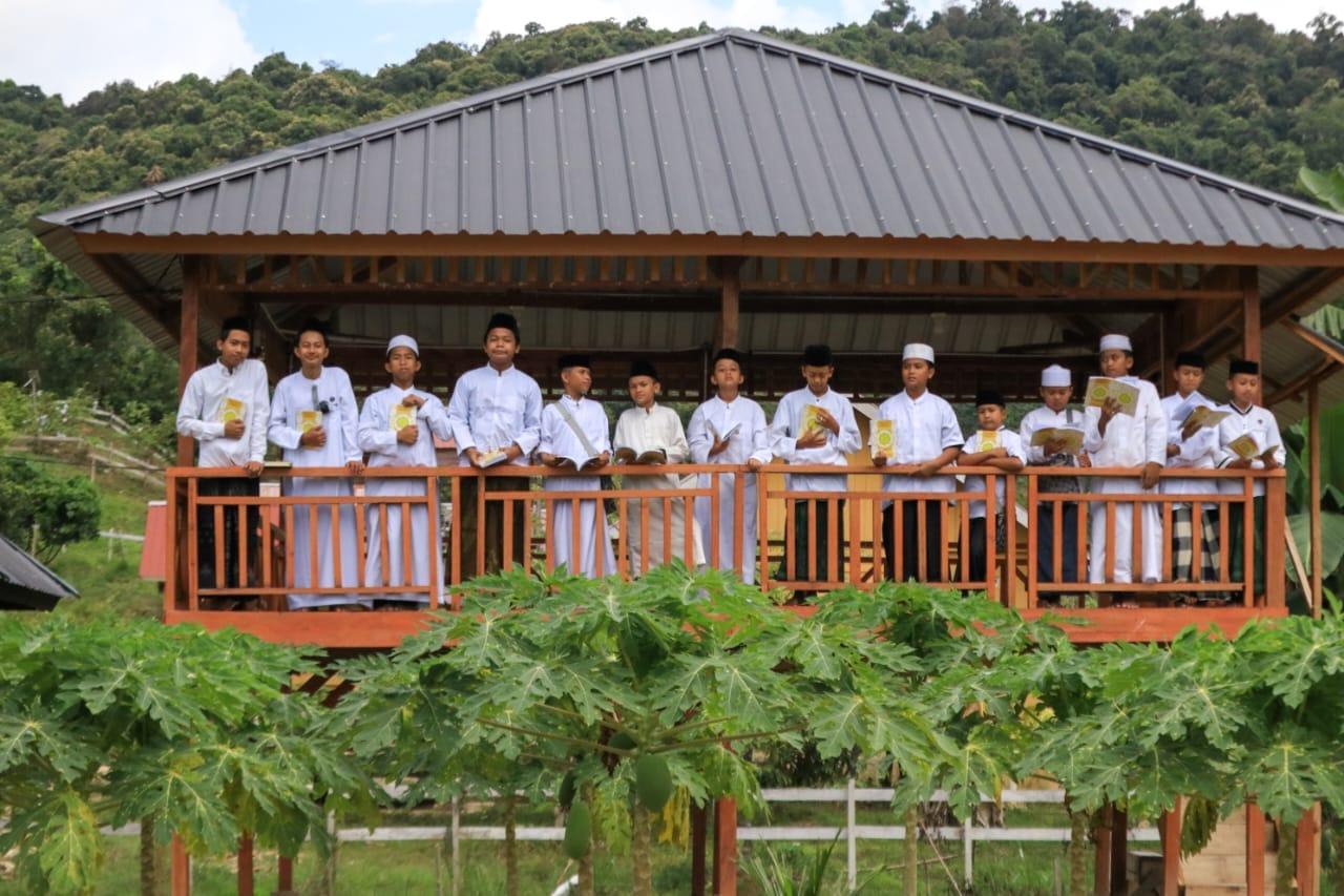 Santri berbaju putih memegang mushaf di gazebo kayu kawasan Agrowisata California