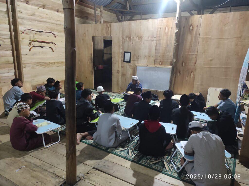 Santri mengaji dan menulis di meja lipat dalam ruang belajar kayu