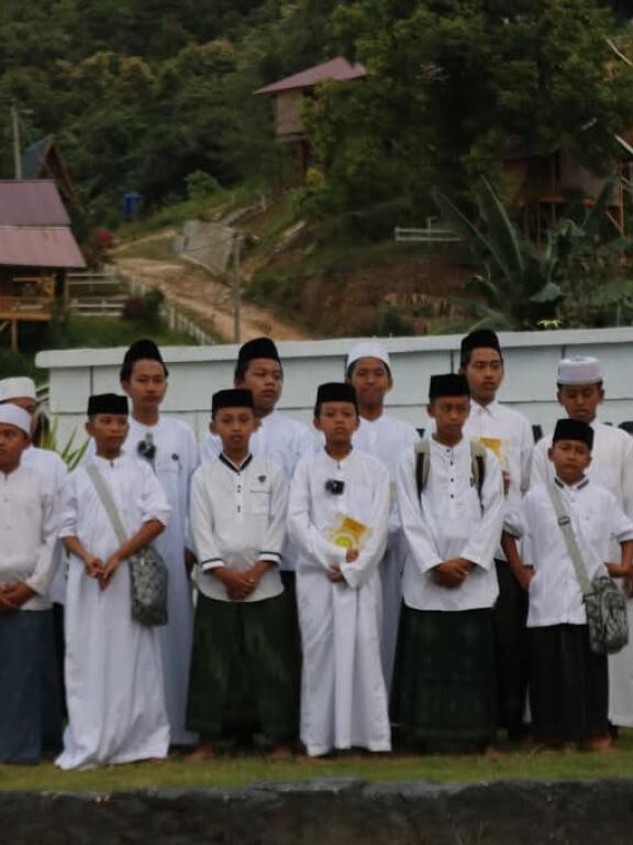 Santri berbaju putih berdiri berjajar di halaman pesantren